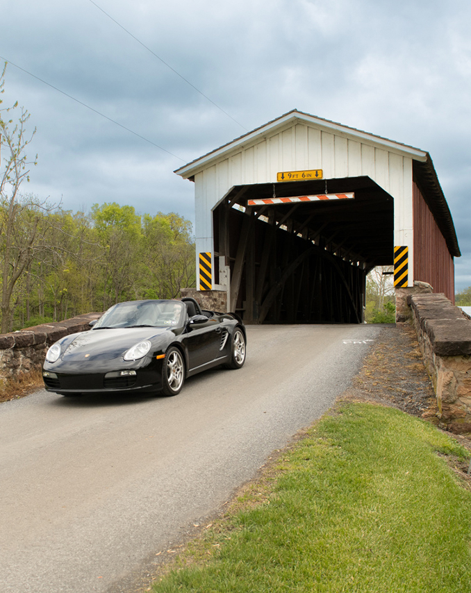 Convertible car drives through a covered bridge in Lancaster County, PA. 